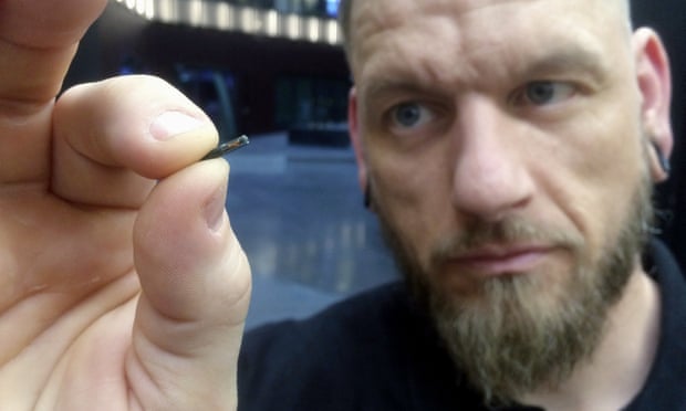 Jowan Österlund from Biohax holds a microchip implant the size of a grain of rice between his thumb and forefinger. Photograph: James Brooks/AP 