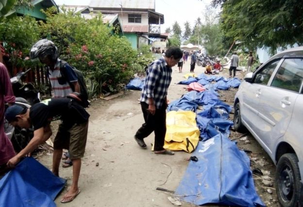 Locals check bodybags in the streets of Palu as they search for lost relatives 