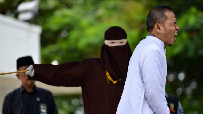 Aceh Ulema Council (MPU) member Mukhlis reacts as he is punished in public