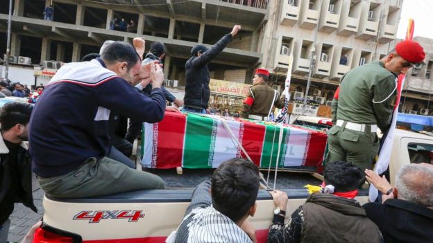Mourners surround a car carrying the coffin of Qasem Soleimani,