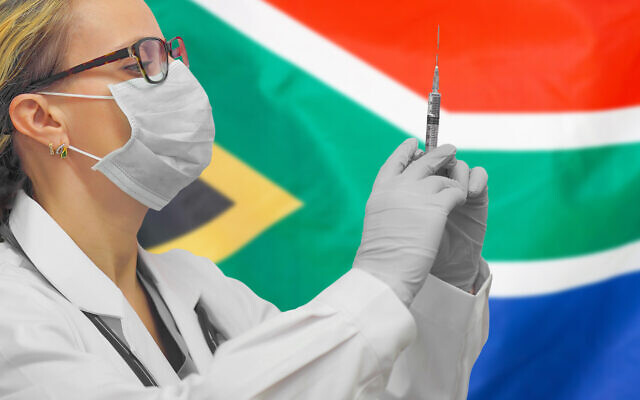 A doctor holding syringe for vaccination against COVID-19, in front of a South African flag. (Igor Vershinsky via iStock by Getty Images)