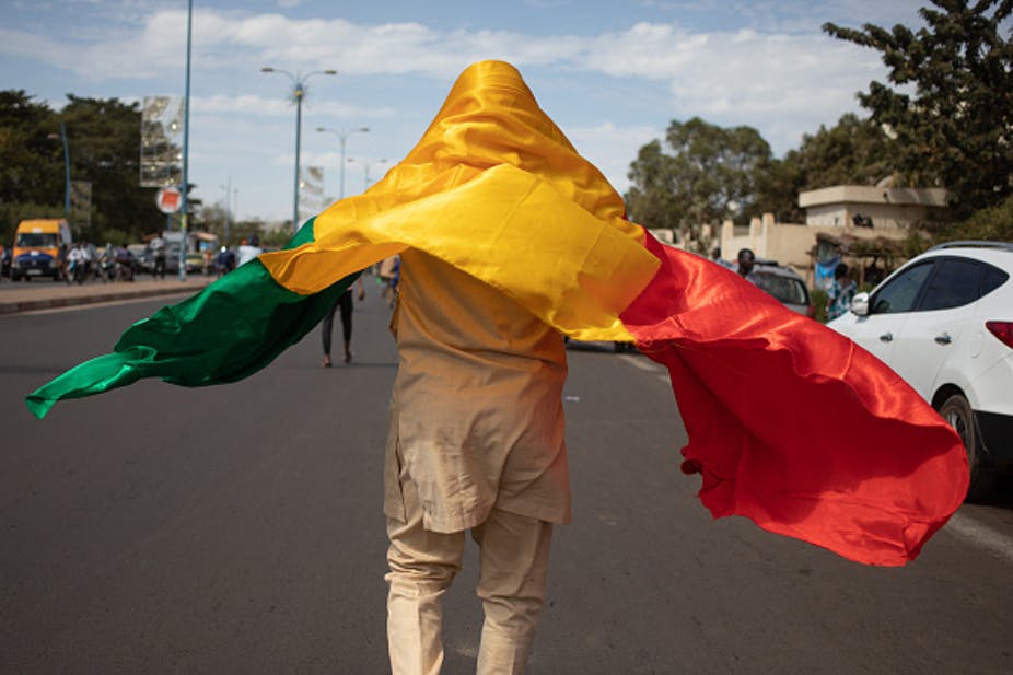 A man with the Malian National flag joins a demonstration in Bamako after the military junta called for protests against sanctions imposed over delayed elections. Photo by Florent Vergnes/AFP via Getty Images